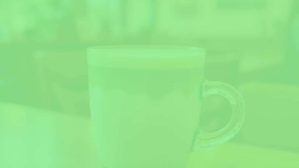 A vibrant Matcha Green Tea Latte in a clear glass cup, with layers of creamy milk and bright green matcha, topped with delicate foam, warm lighting, cozy café background, realistic.