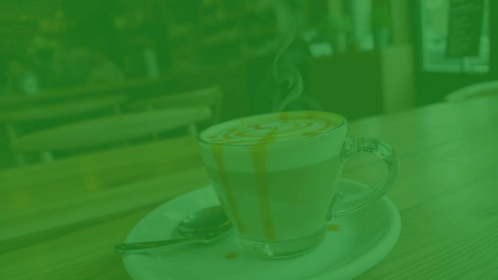 A steaming flavored cappuccino with a creamy foam top, drizzled with caramel syrup, on a wooden table, cozy coffee shop ambiance, realistic.